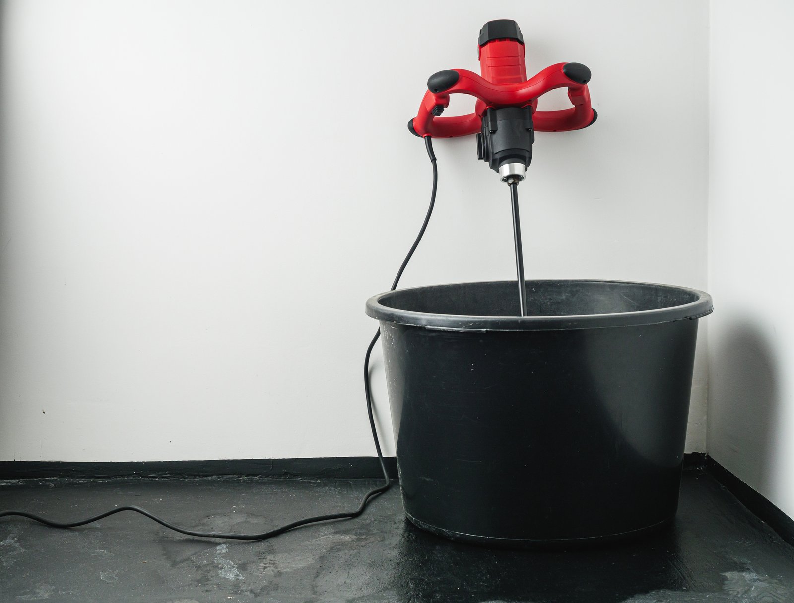 handheld electric concrete mixer on construction site.