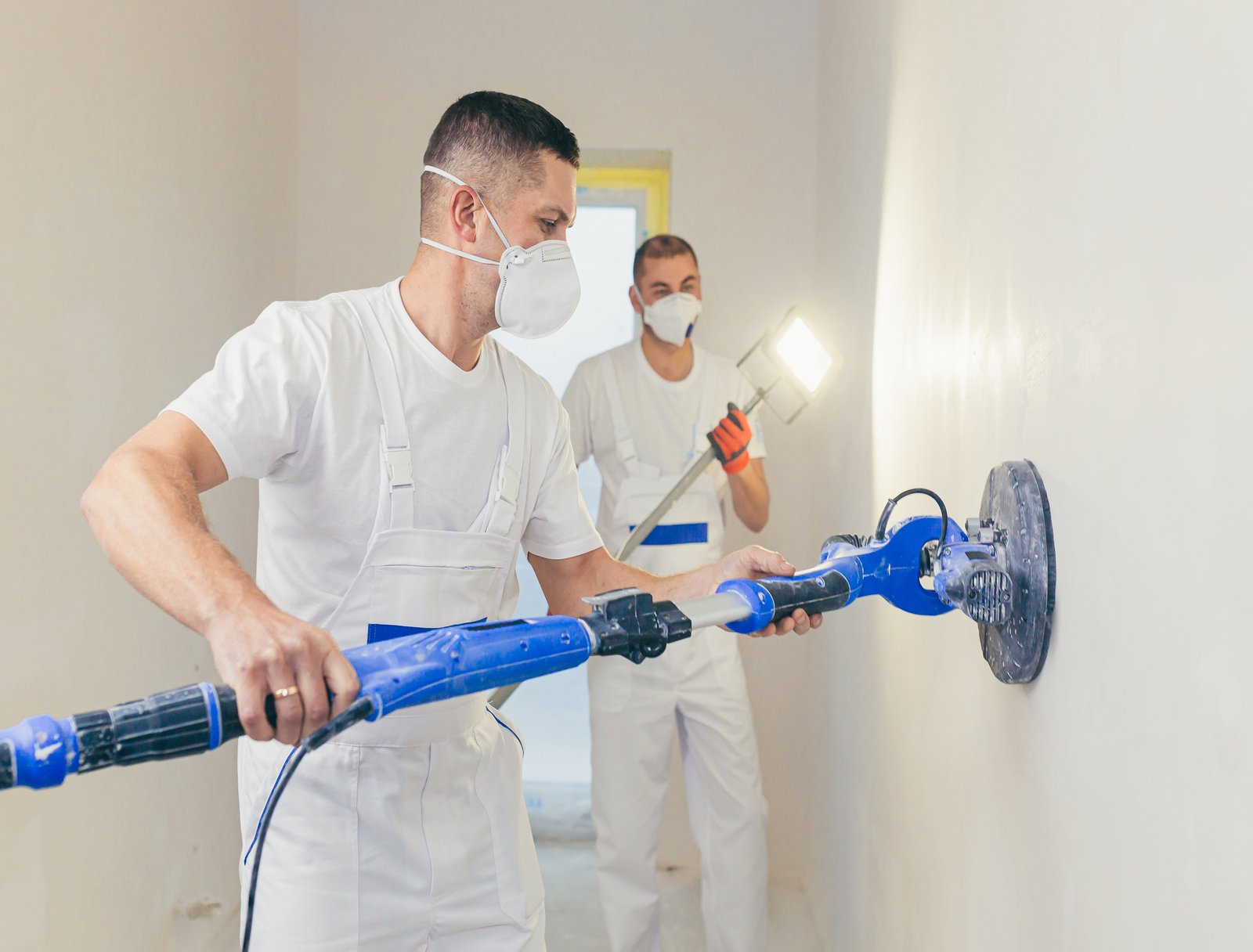 plasterer-smoothes-wall-surface-with-wall-machine-with-sandpaper