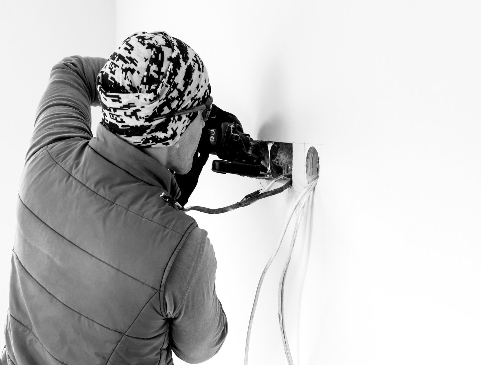 Worker cuts a hole in the wall. Installing new outlets. Work with an electric tool or angle drive grinder. dangerous job. Professional Electromechanical installation. sparks from cutting metal.